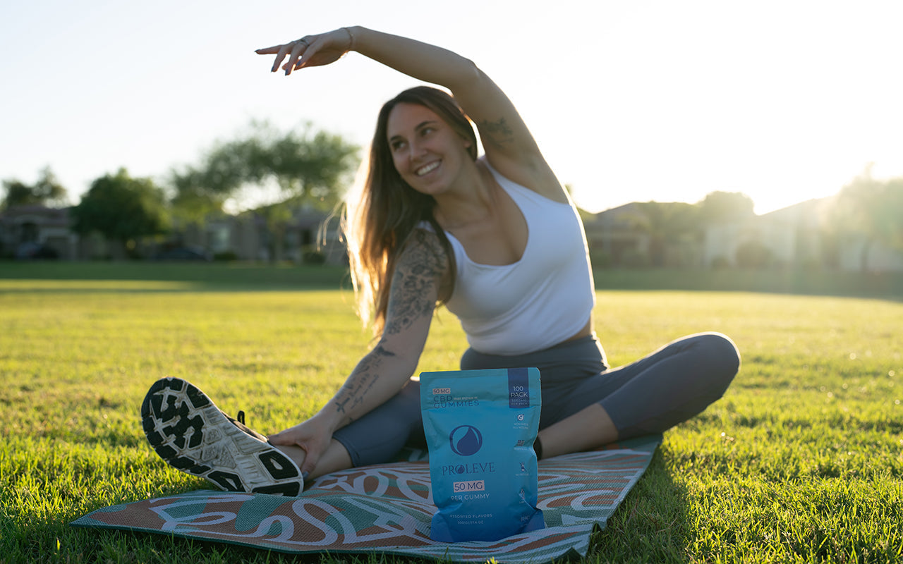 Girl in field stretching on yoga mat with a pack of cbd gummies