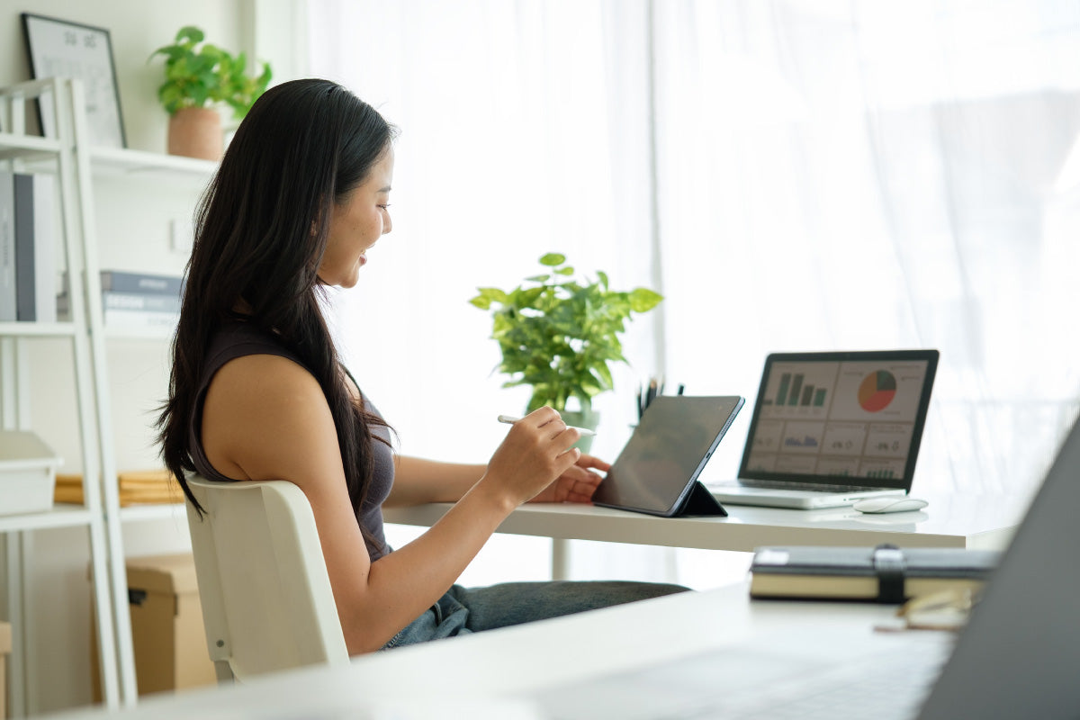 woman at desk looking at graphs on lap top