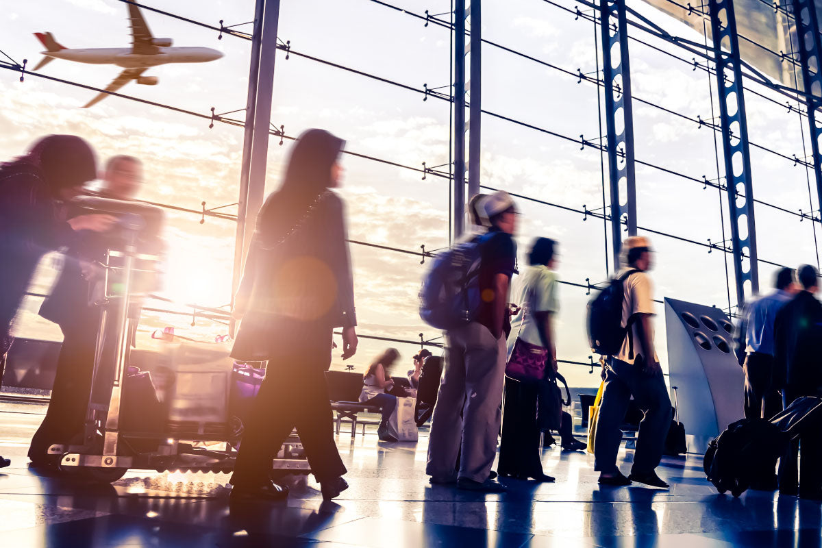 image of people walking thru an airport with airplan flying in background