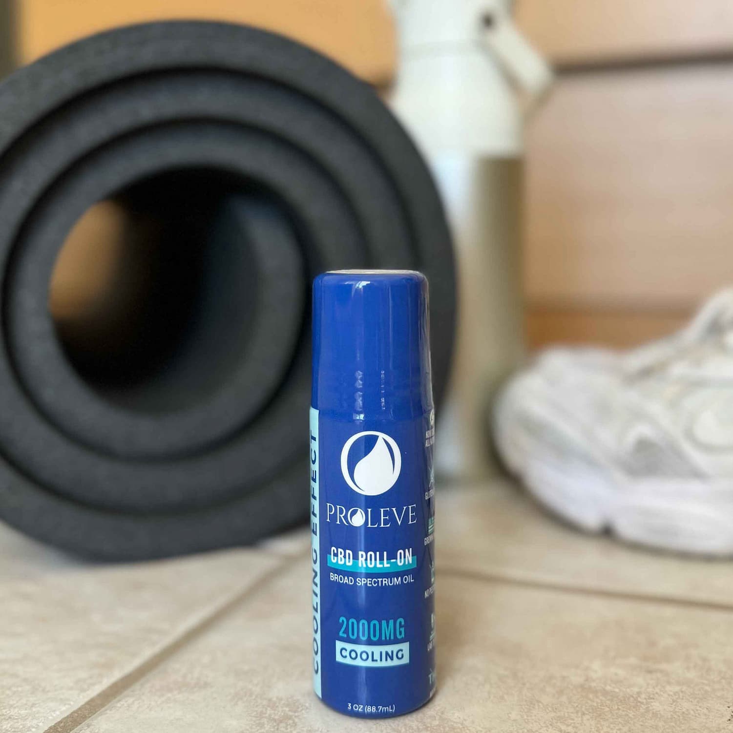 Blue Pro leve CBD roll-on bottle on a tiled floor with a black mat and white shoe in the background.