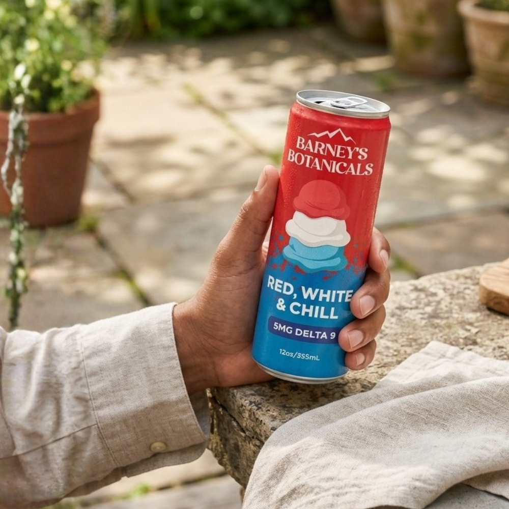 Hand holding a can of 'Barney's Botanicals Red, White & Chill' outdoor setting