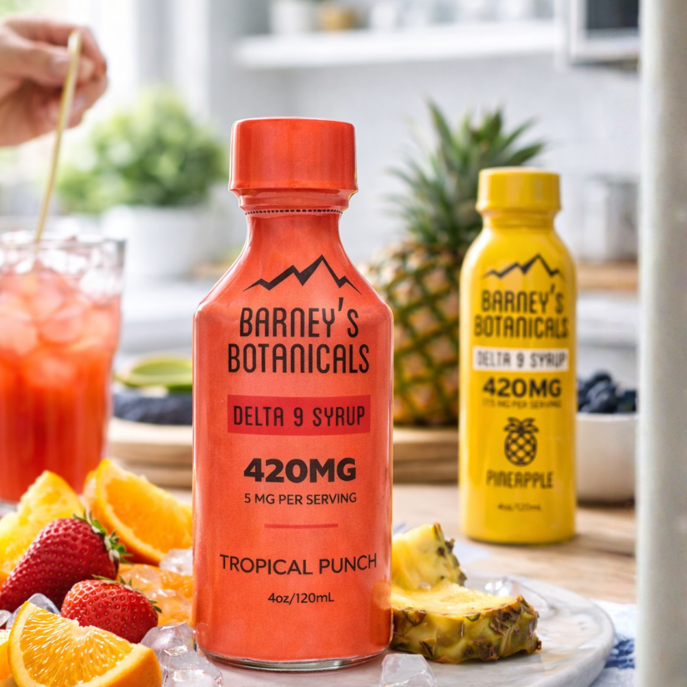 Two bottles of Barney's Botanicals Delta 9 Syrup on a table with fruits and drinks.